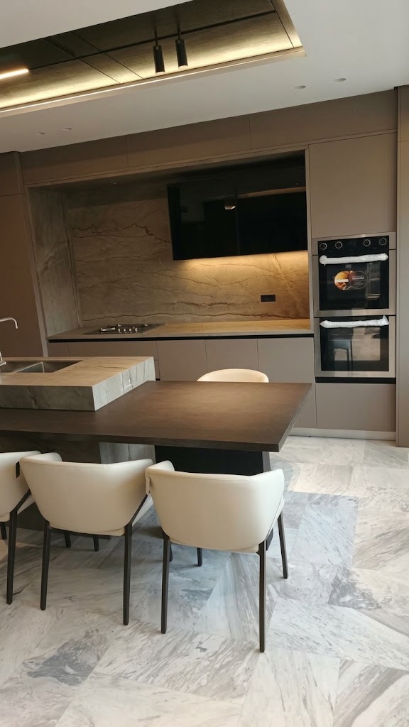 Cocina contemporánea con isla de piedra, comedor y hornos empotrados